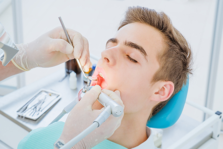 Can An Emergency Dentist Do A Root Canal Dentist Performing Dental Procedure Using Tools And Light On Patient In Chair