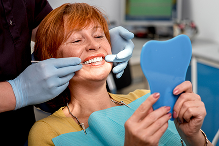 Photo Dentist Holding Shade Guide To Patient Teeth While She Looks In Handheld Mirror
