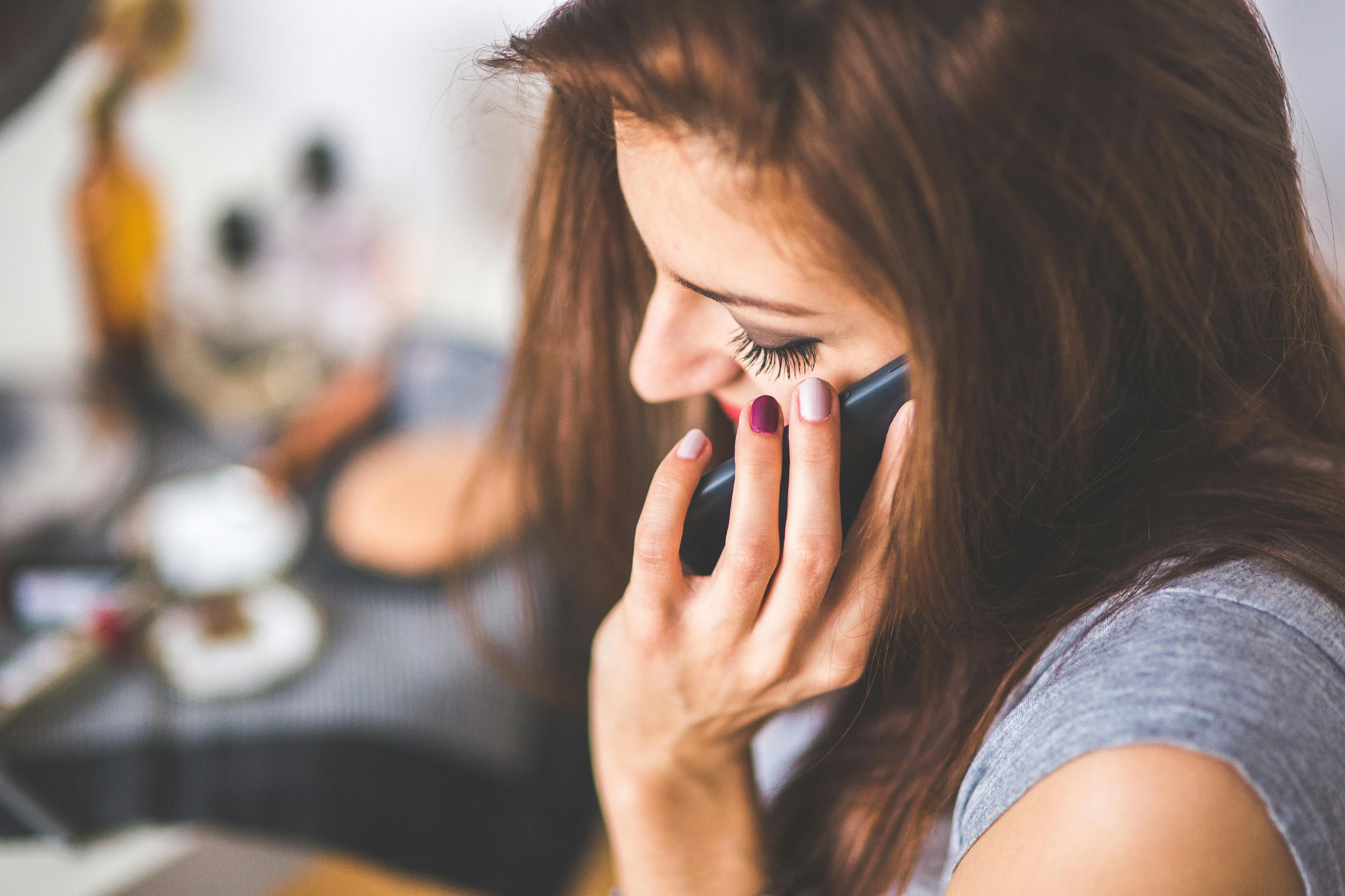 Photo Woman With Long Brown Hair Holding Phone To Ear Looking Down As If Asking Is Losing A Filling A Dental Emergency
