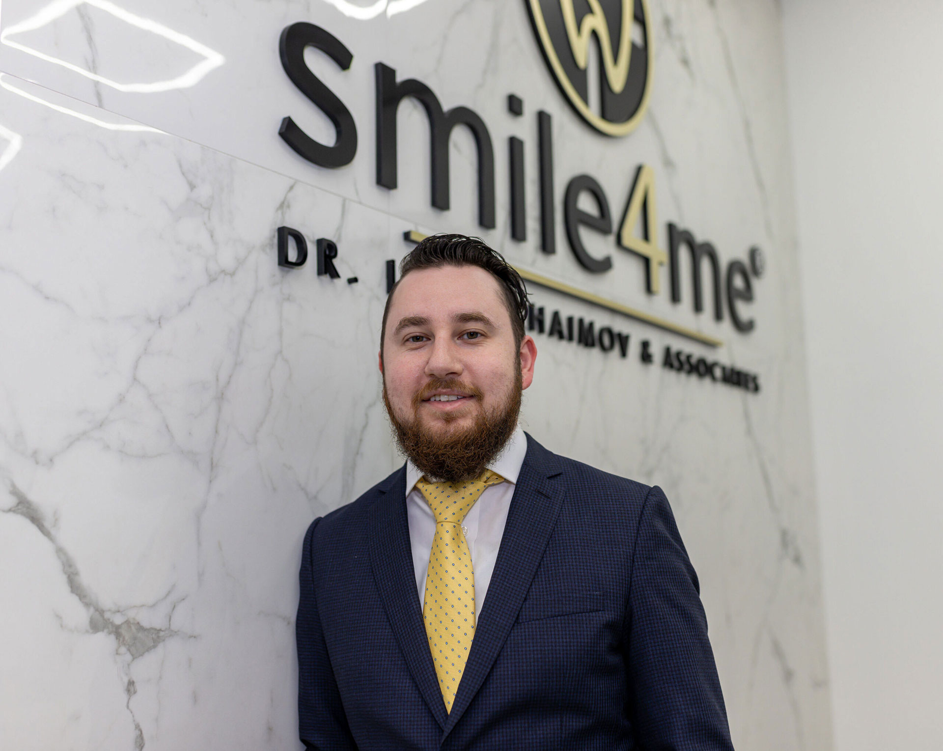 Photo Man In Suit Standing In Front Of Smile4me Dental Care Wall Sign Inside Clinic