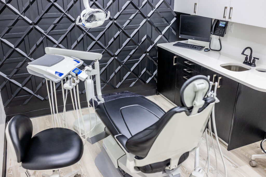 Photo Modern Dental Chair Equipment Overhead Light Monitor Sink And Black Geometric Wall Design In Clinic Room