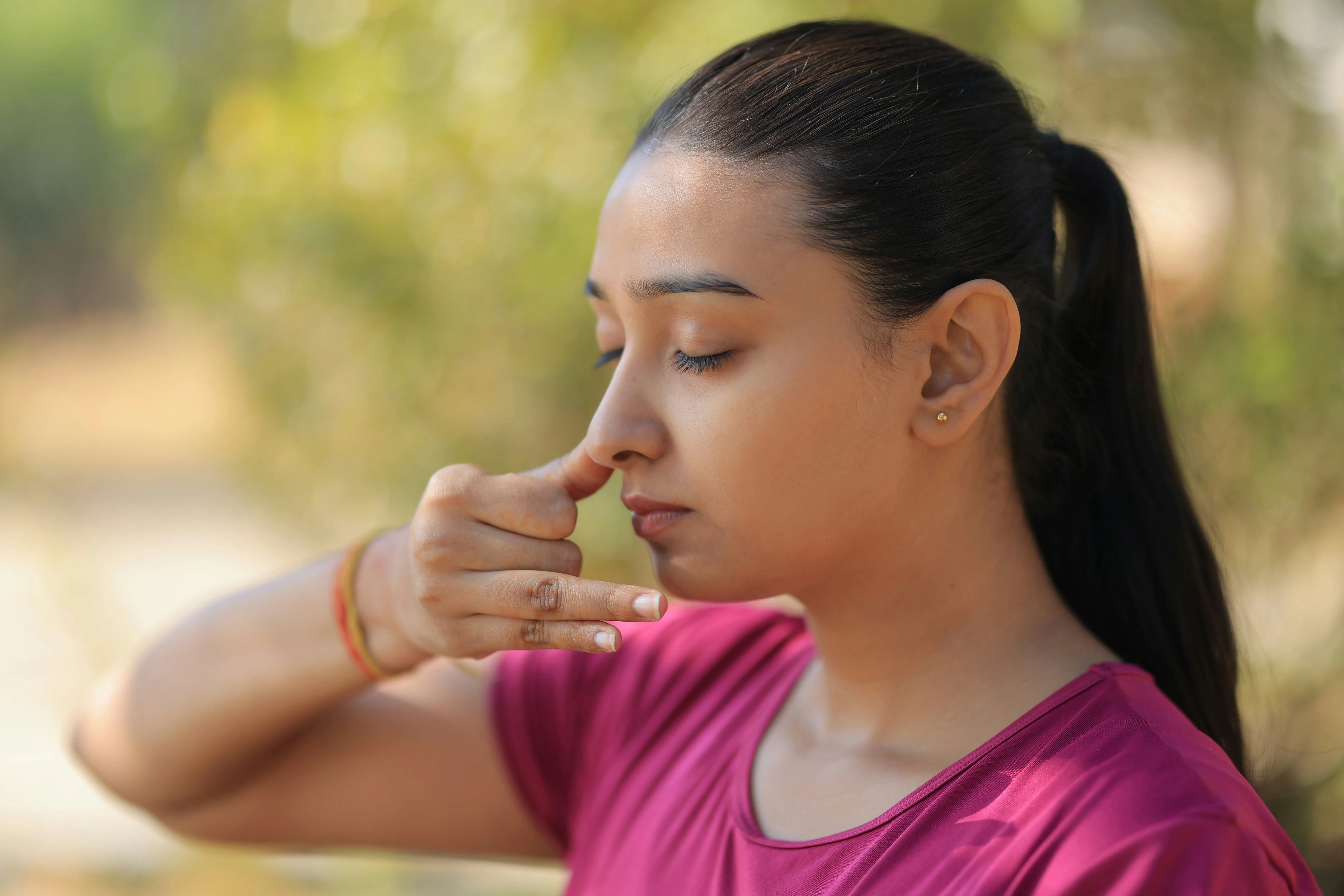 Photo Woman With Eyes Closed Practicing Breathing Exercise While Holding One Nostril Outdoors In Daylight