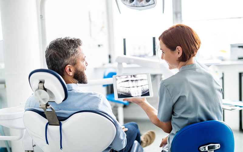 Photo Dentist Showing Dental X Ray To Patient Asking Will An Emergency Dentist Remove A Wisdom Tooth