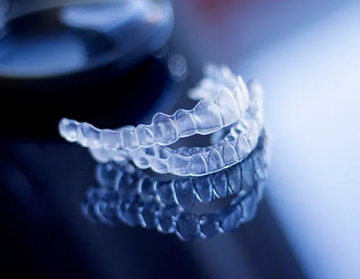 Clear Invisalign Aligners Stacked On Reflective Surface Used To Illustrate Patient Question Does Invisalign Hurt During Treatment