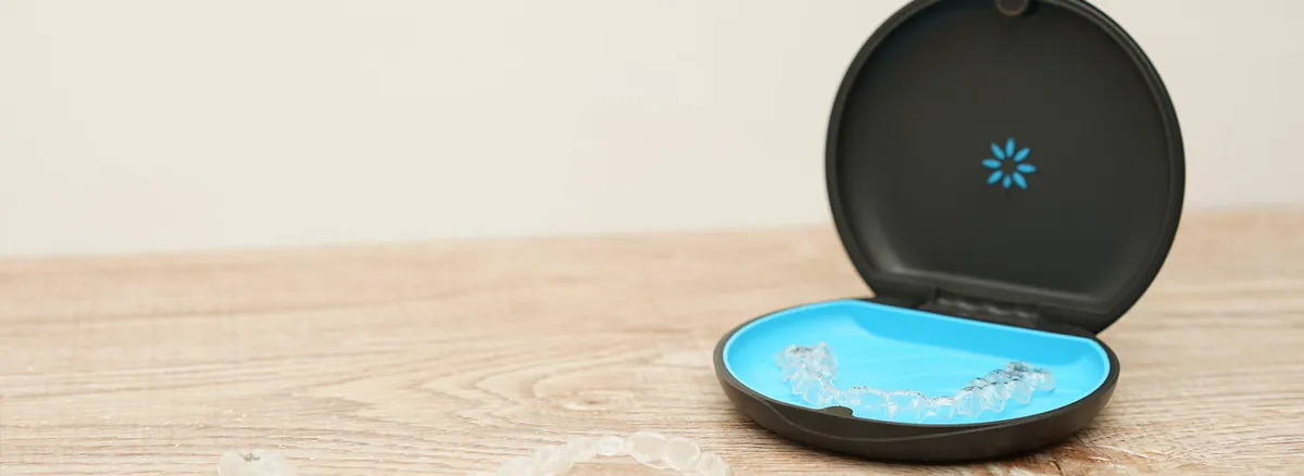 Clear Invisalign Aligners Inside Black And Blue Case On Wooden Surface Showing Storage Solution For Patients Asking Does Invisalign Hurt