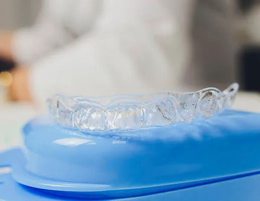 Clear Invisalign Aligner Resting On Blue Case In Dental Office Setting Representing What Happens After Invisalign Treatment And How Retainers Are Used
