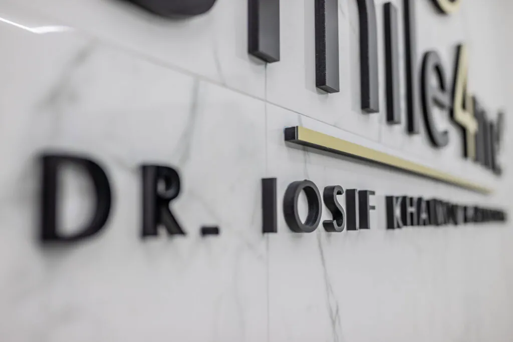 Close Up Of Office Wall Sign Showing Dr Iosif Khaimov Name And Smile4me Logo On Marble Background